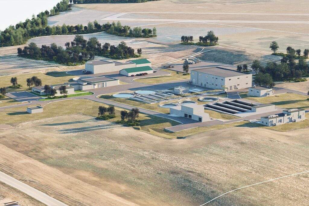 Aerial view of a water treatment plant, part of ALASD Projects, surrounded by grass and trees, featuring multiple buildings, circular water tanks, and large pipelines in a rural landscape.