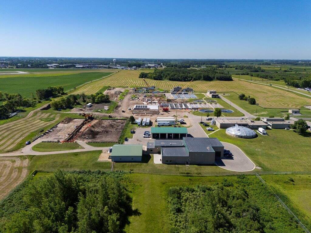 Aerial view of a large rural facility with several buildings, ongoing construction, equipment, open fields, and green areas under a clear blue sky—a testament to recent WRF Improvements.